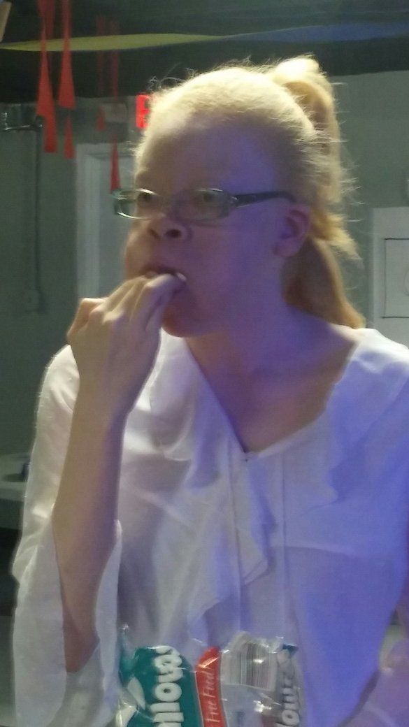A woman wearing glasses and a white shirt is eating something