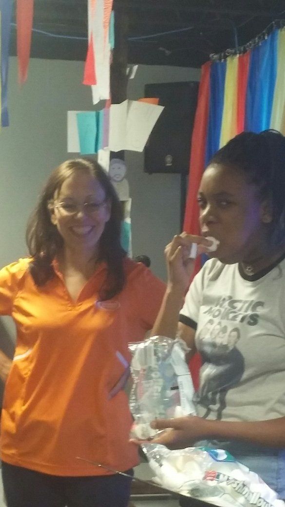 Two women are standing next to each other and one is eating something