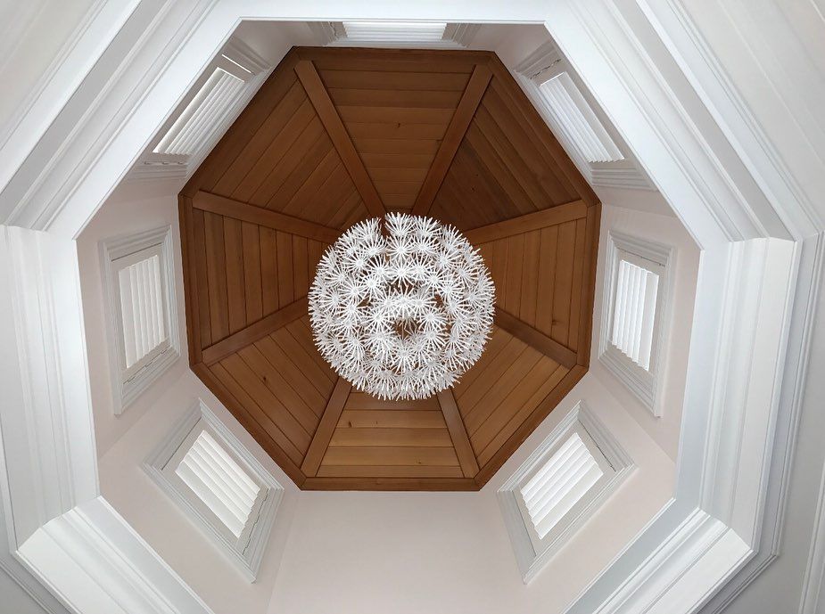 A textured circular chandelier in the cupola of a room.