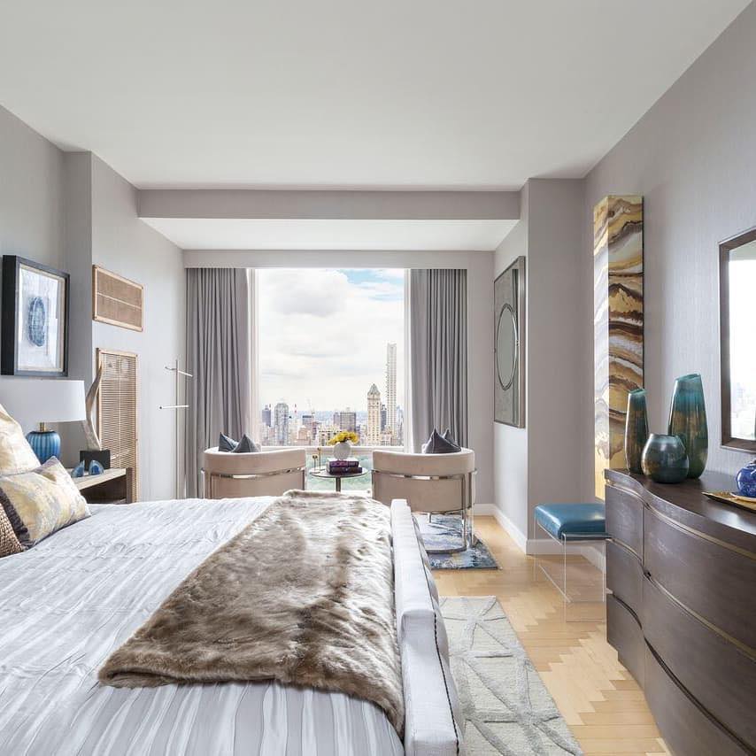 A bedroom with custom drapery and a city skyline view 