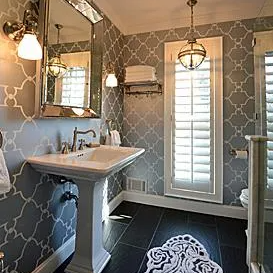 A bathroom with patterned wallpaper and custom shutters
