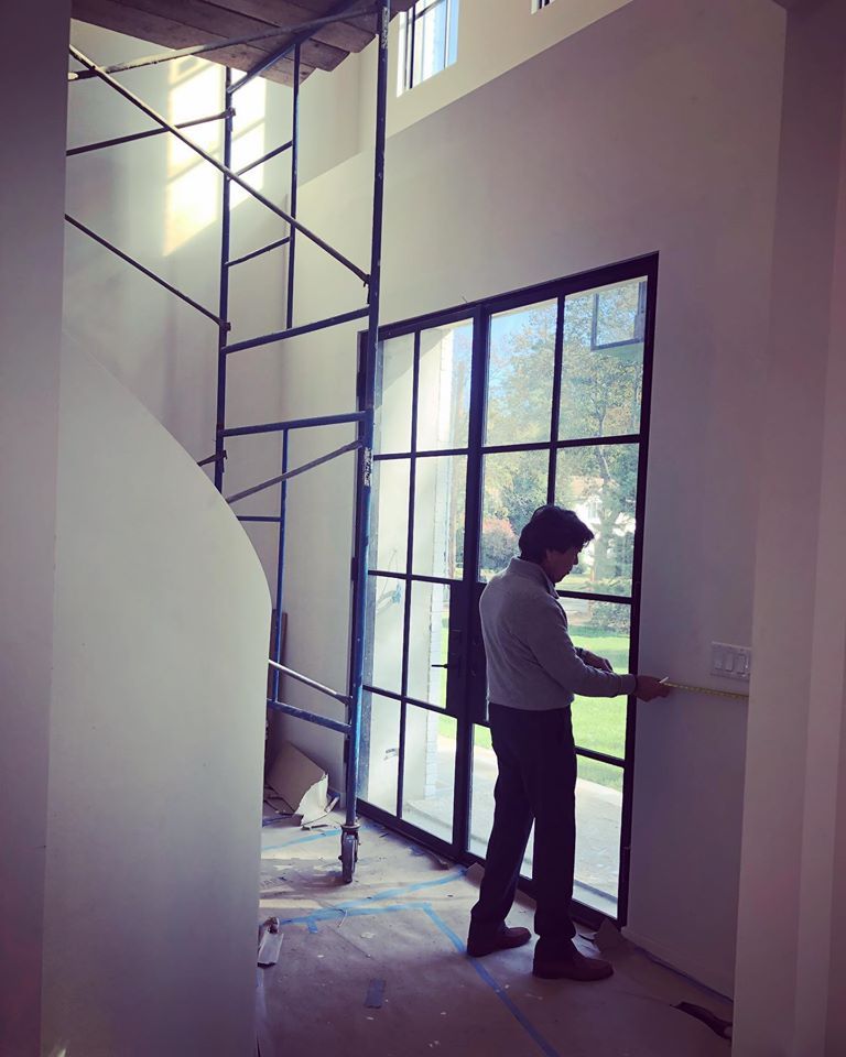 A professional measuring near a pair of French doors