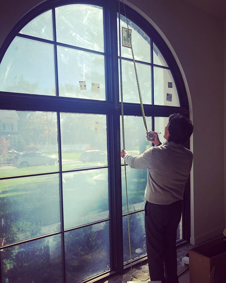 A window treatment expert measuring an arched window