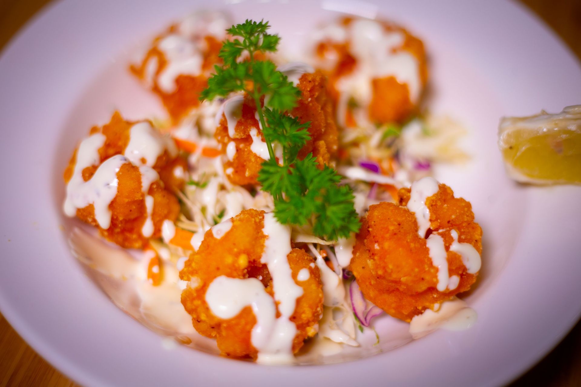 A close up of a plate of food with shrimp and coleslaw on a table.