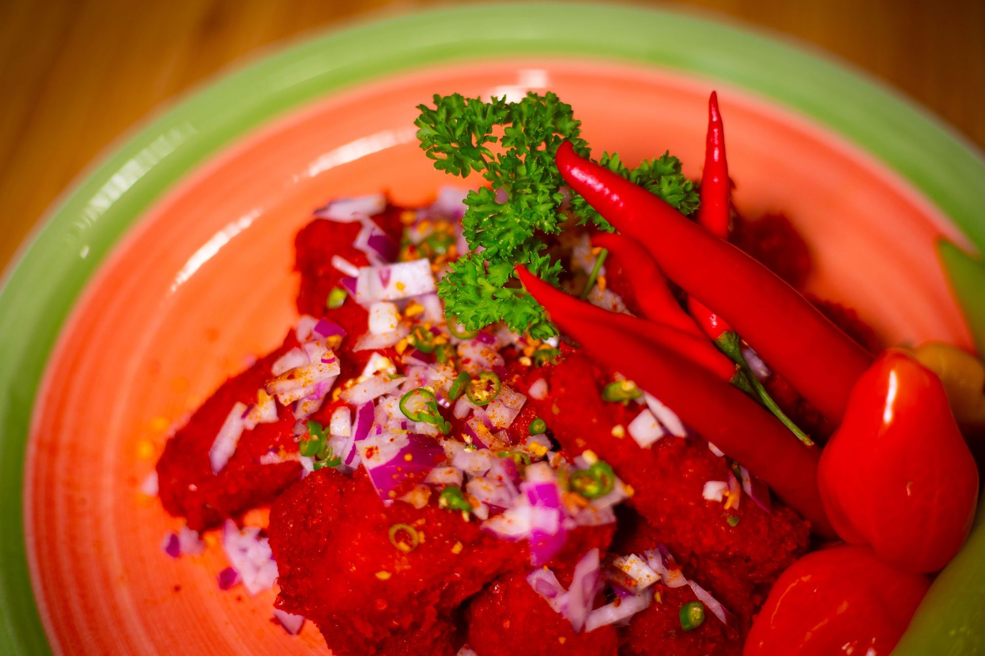 A plate of food with red peppers , onions and parsley on a table.
