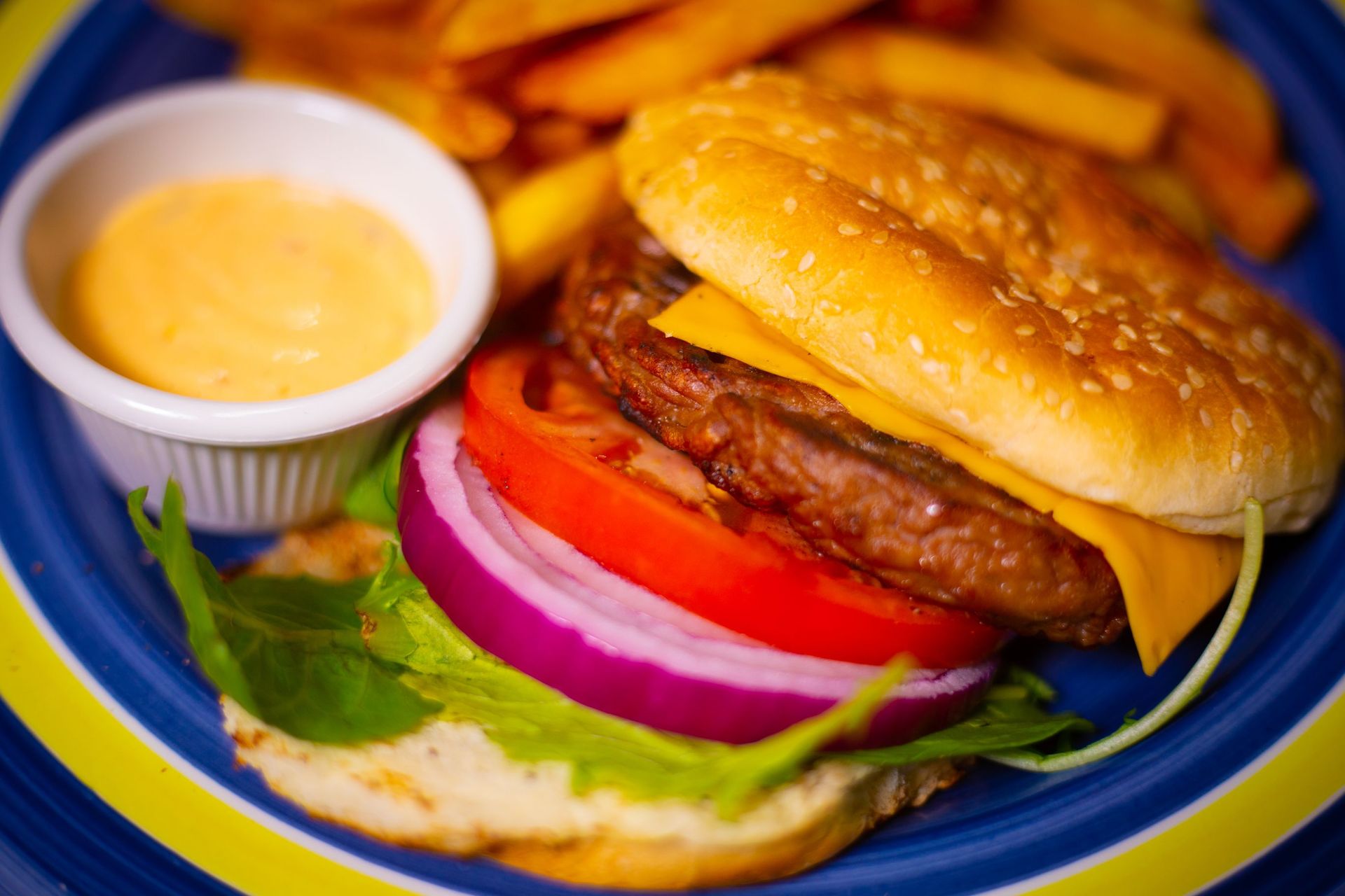 A close up of a hamburger and french fries on a blue plate.