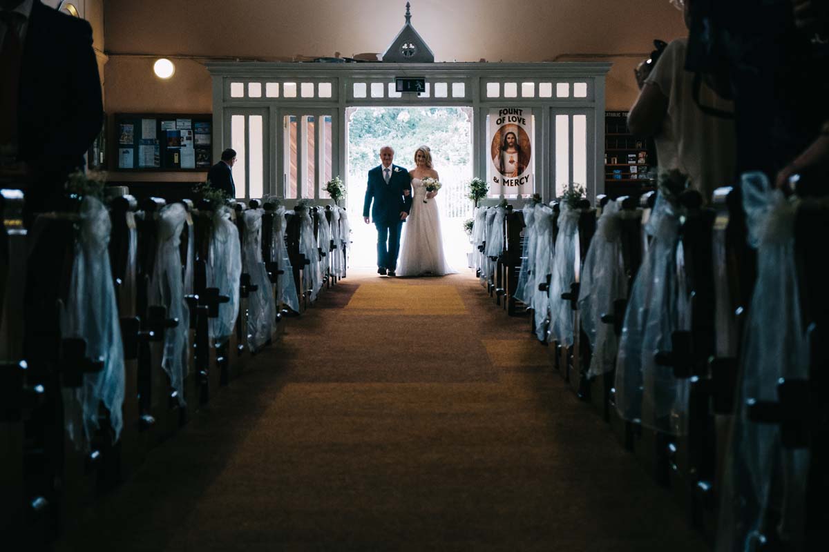 wedding photographer bandon - bride coming down the aisle with father
