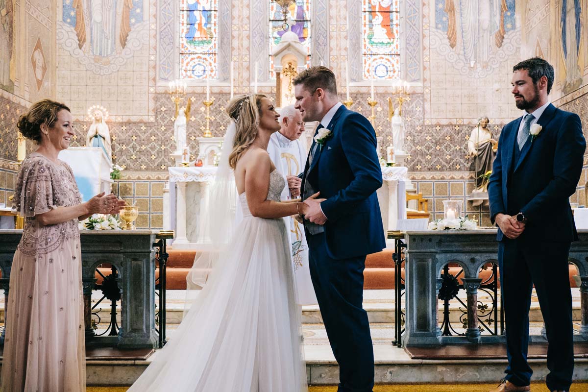 Kinsale wedding photographer - bride and groom engage in first kiss after marriage ceremony   