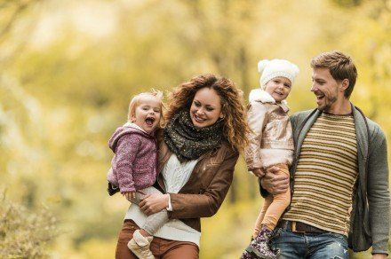 Happy parents enjoying with their two daughters outdoors while walking.
