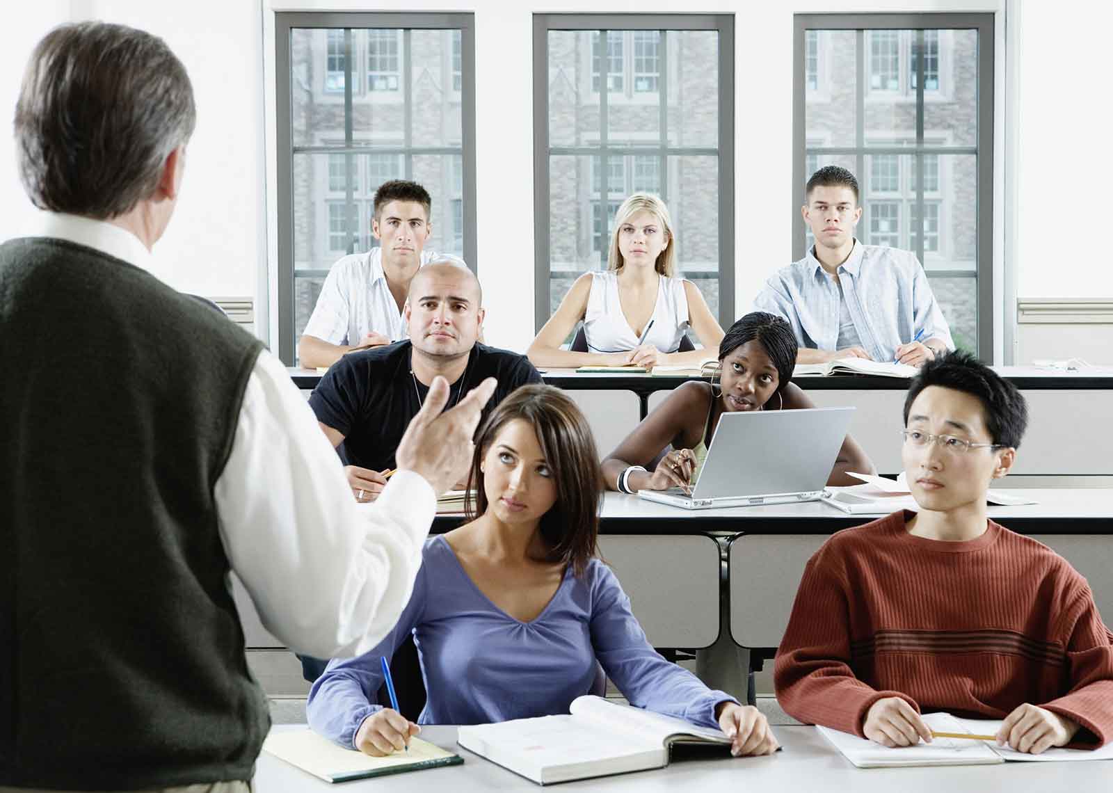 The back of a man addressing an audience of university level students.