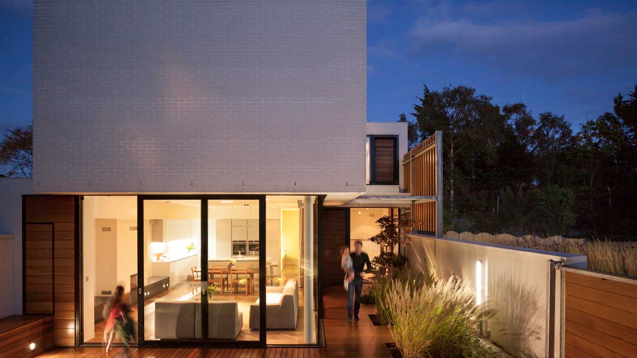 Evening shot of a glass and white brick modern house exterior in Clontarf