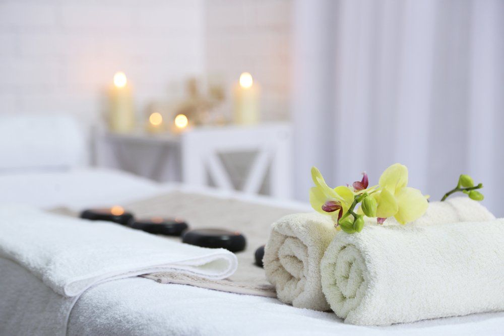 Ein Massagetisch mit Handtüchern, Blumen und Kerzen darauf.