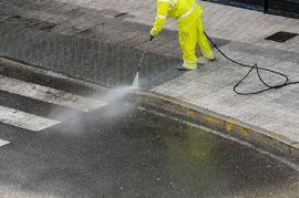Worker cleaning the sidewalk with pressurized water