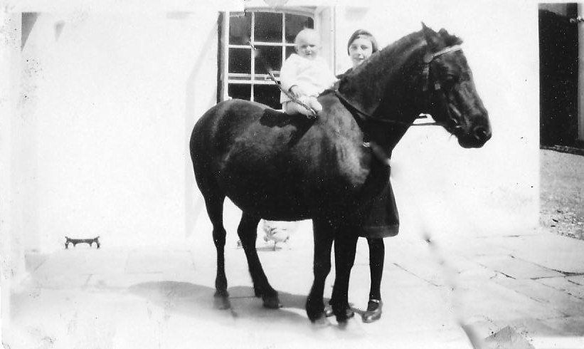 Child sat on a horse with mother by side