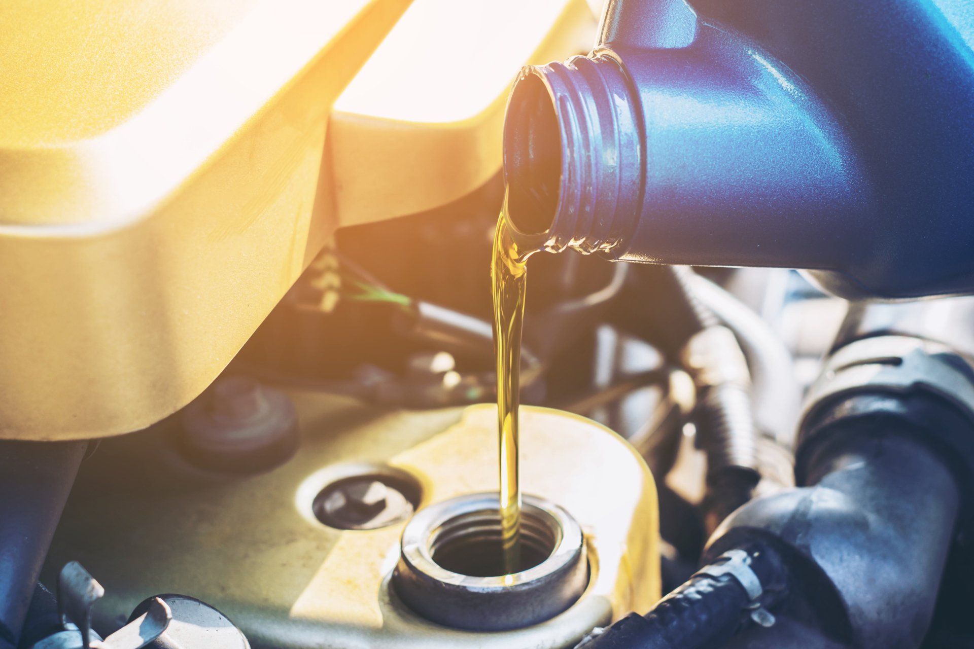 A close up of a person pouring oil into a car engine.