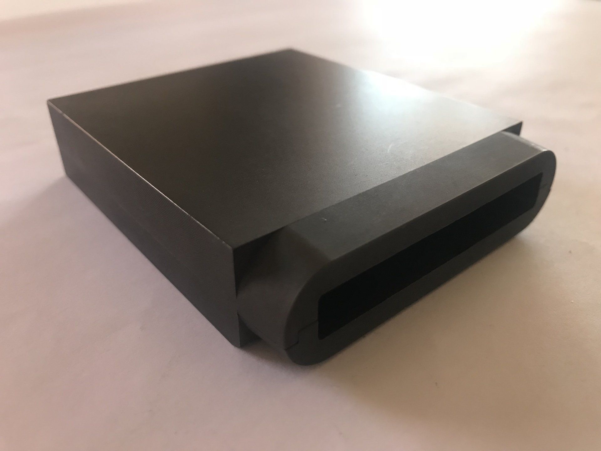 Auf einer weißen Fläche steht eine schwarze Box.