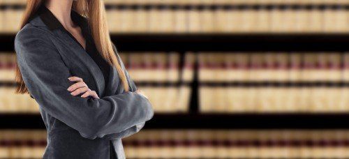 Donna in piedi a braccia conserte davanti a una biblioteca