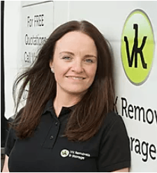 Woman with brown hair in black shirt smiles in front of a VK Removals & Storage logo.