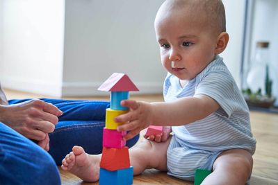 Baby Playing With Coloured Wooden Blocks — Burtonsville, MD — Childway Early Learning Center Baby Playing With Coloured Wooden Blocks — Burtonsville, MD — Childway Early Learning Center