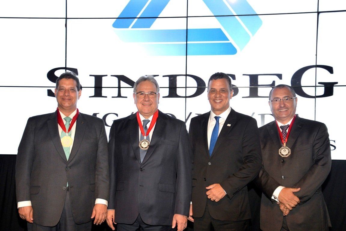 Um grupo de homens em pé em frente a uma placa que diz sindseg