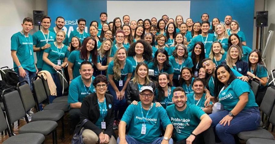 Um grande grupo de pessoas está posando para uma foto em uma sala.
