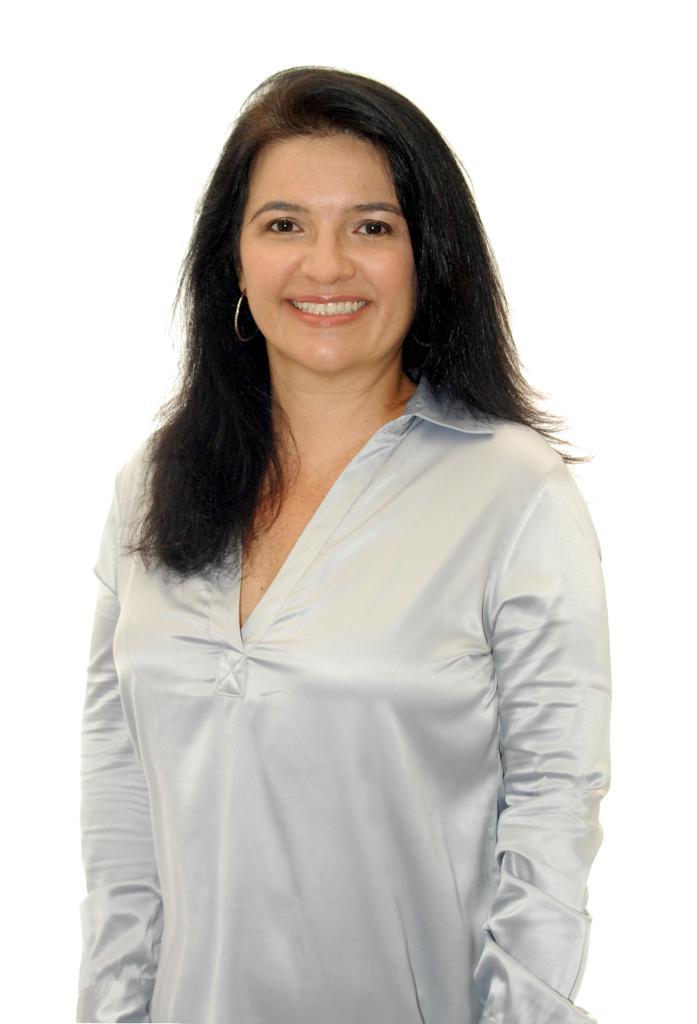 Uma mulher de camisa branca está sorrindo para a câmera.