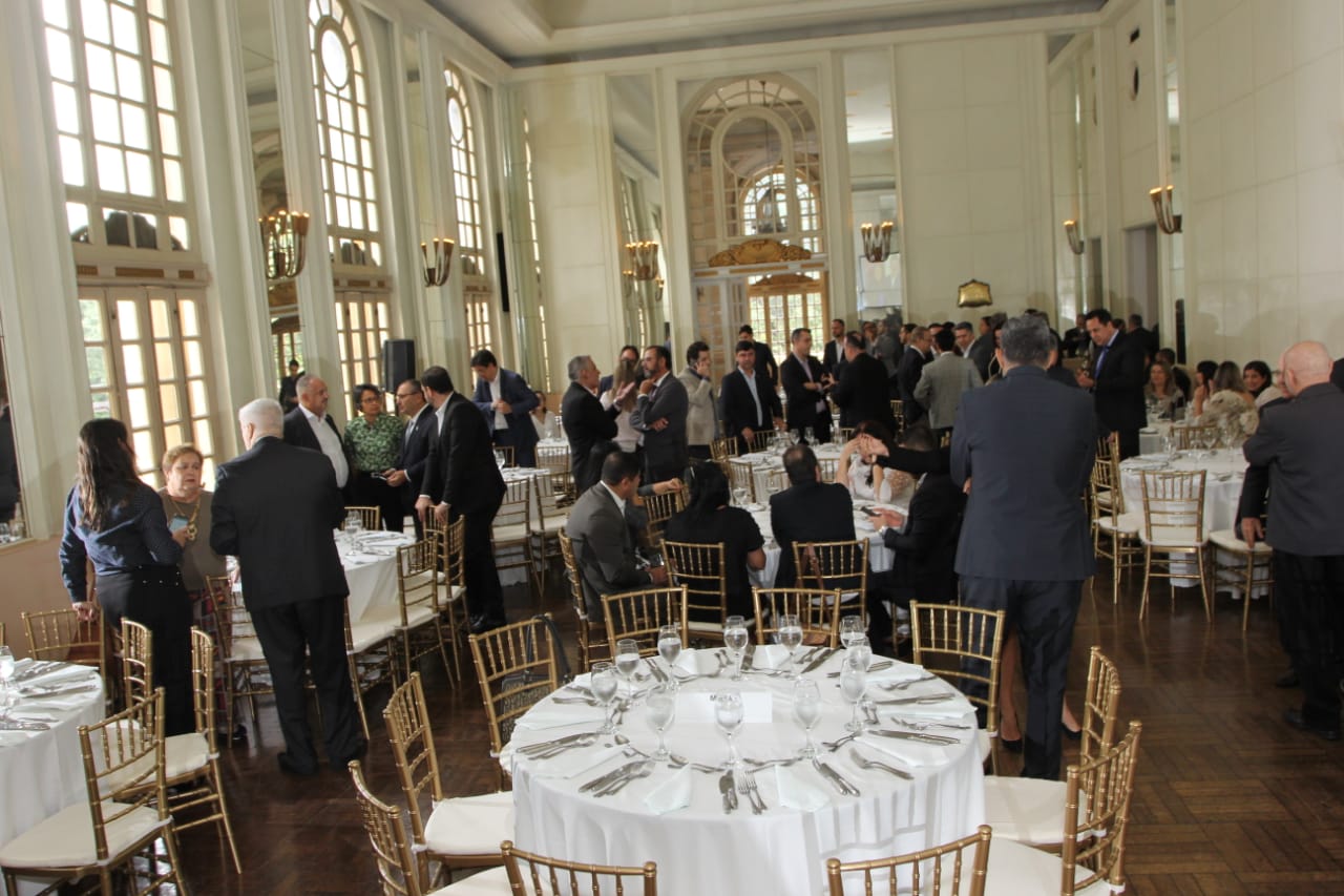 Um grupo de pessoas está sentado em mesas em uma sala grande.