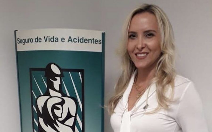 A woman stands in front of a sign that says seguro de vida e acidentes