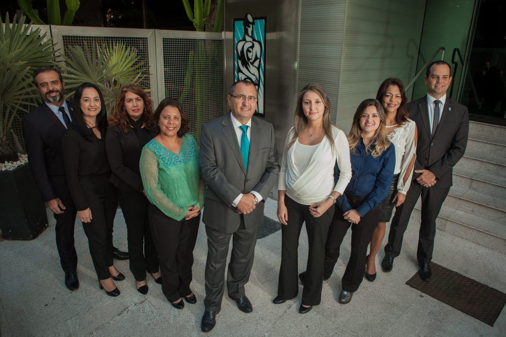 Um grupo de pessoas em pé, uma ao lado da outra, em frente a um prédio.