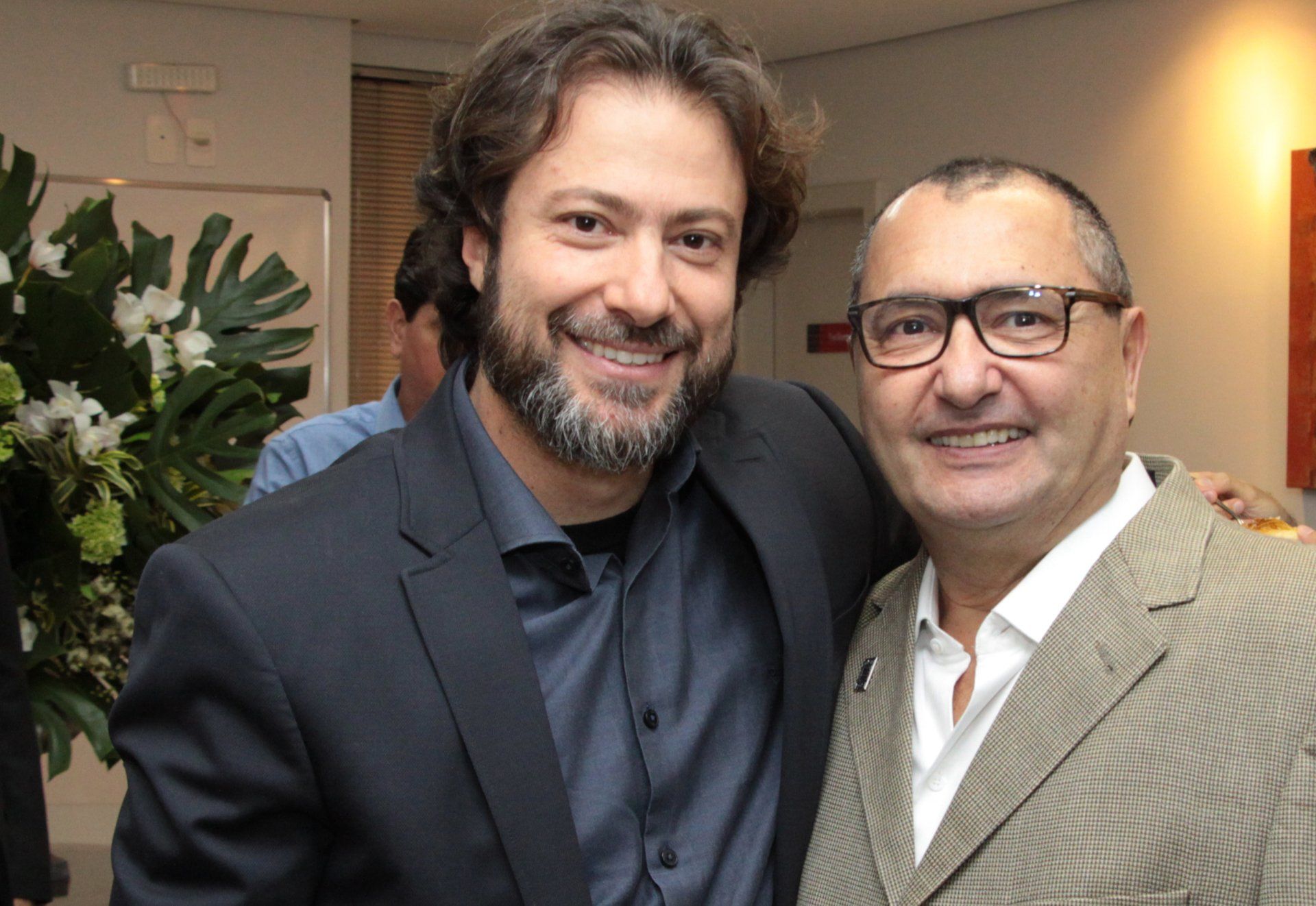 Dois homens estão posando juntos para uma foto e sorrindo para a câmera.