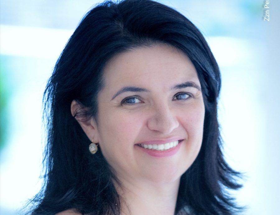Uma mulher de cabelos escuros está sorrindo para a câmera