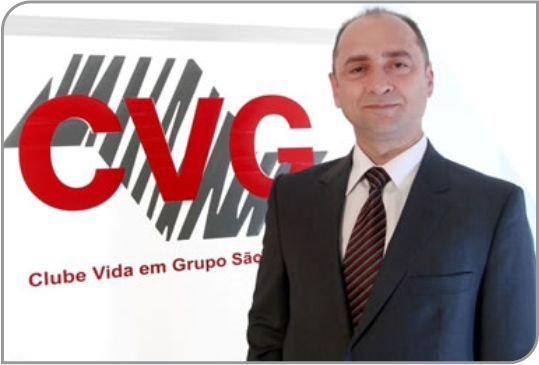 Um homem de terno e gravata em frente a um logotipo de GNC