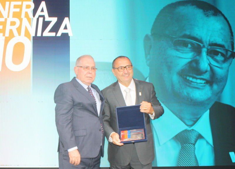 Dois homens em pé em frente a uma placa que diz nera erniza 10