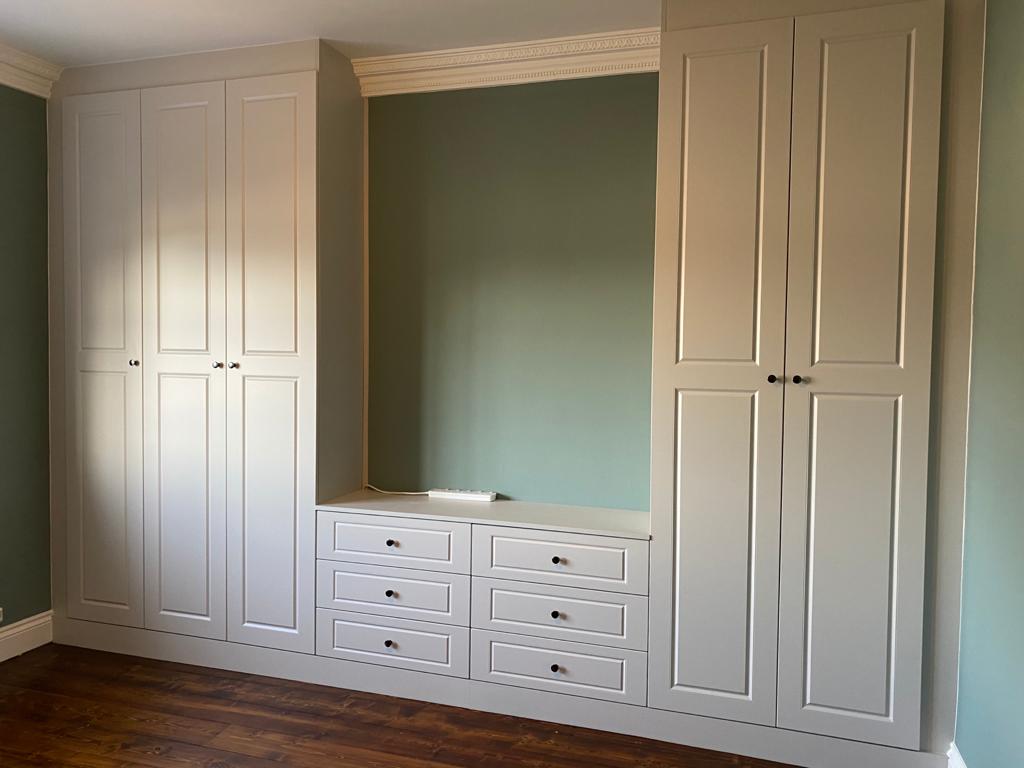 A room with a lot of white cabinets and drawers