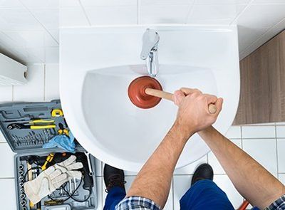 Male Plumber Using Plunger in Bathroom Sink — Fort Myers, FL — Panther Plumbing Inc. Male Plumber Using Plunger in Bathroom Sink — Fort Myers, FL — Panther Plumbing Inc.