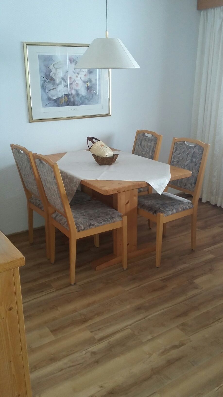 Ein Esszimmer mit einem Tisch und Stühlen und einem Bild an der Wand.