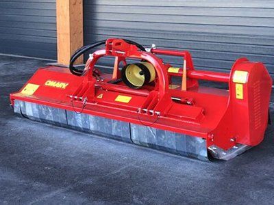 Ein roter Traktor steht vor einem Garagentor.