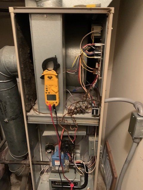 A clamp meter is plugged into the inside of a furnace.