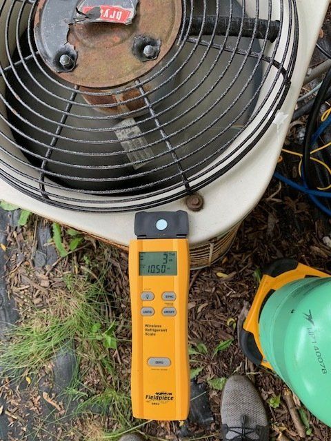 A thermometer is sitting on the ground next to an air conditioner