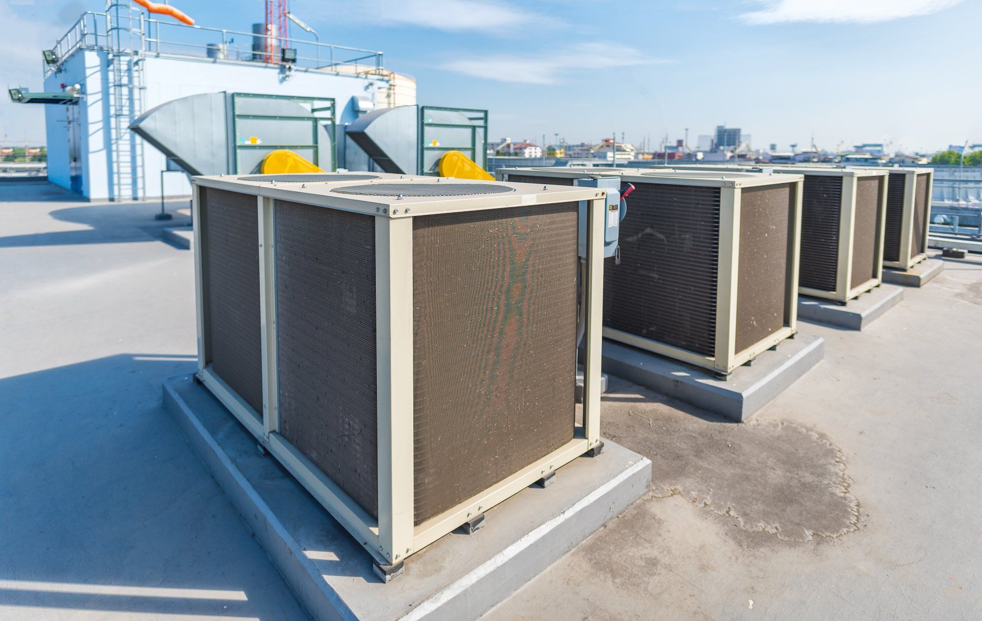 A row of air conditioners are sitting on top of a roof.
