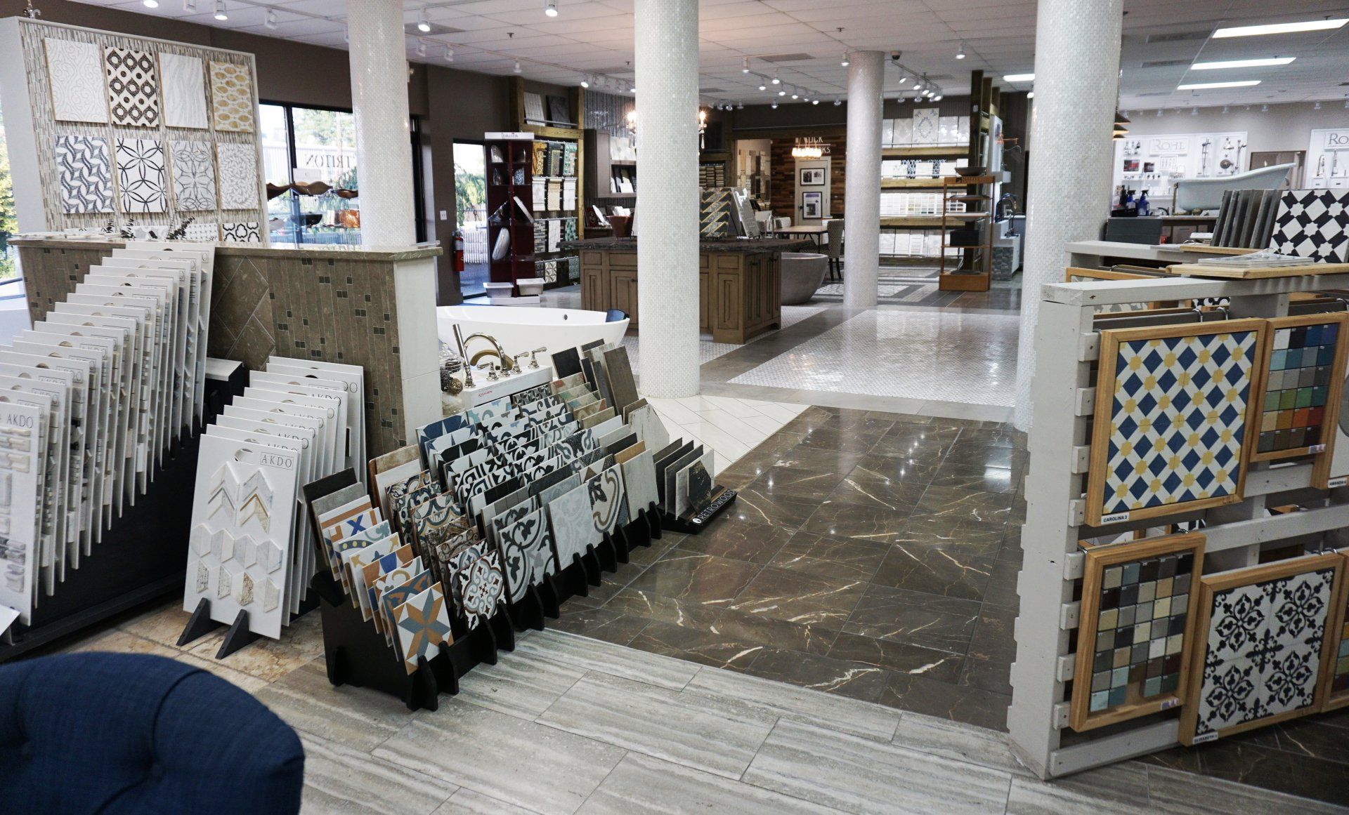 Interior of a tile store with displays of various tiles, columns, and a sitting area.