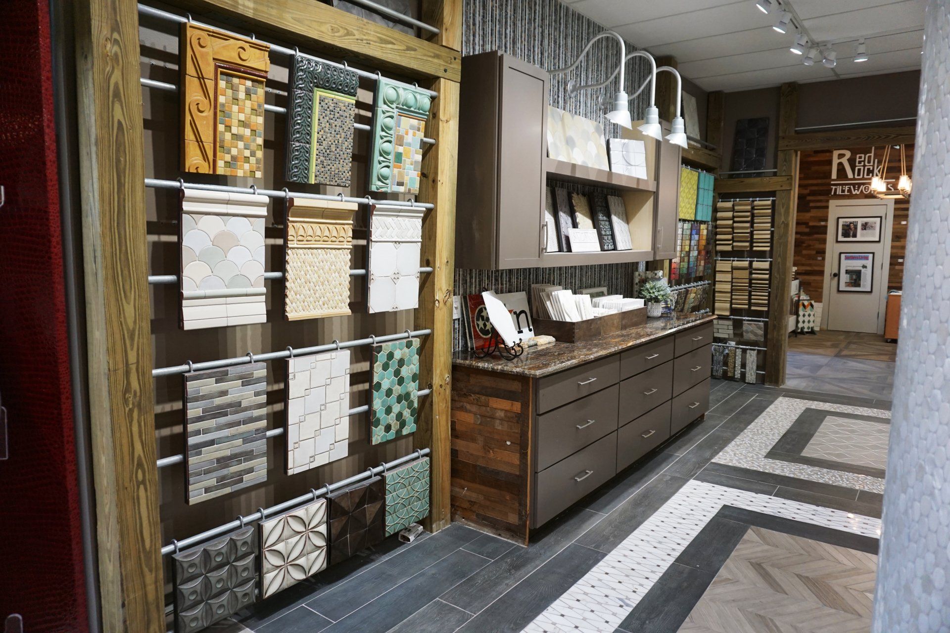 Interior design showroom, tile samples displayed on wood, cabinets with samples, varied flooring.