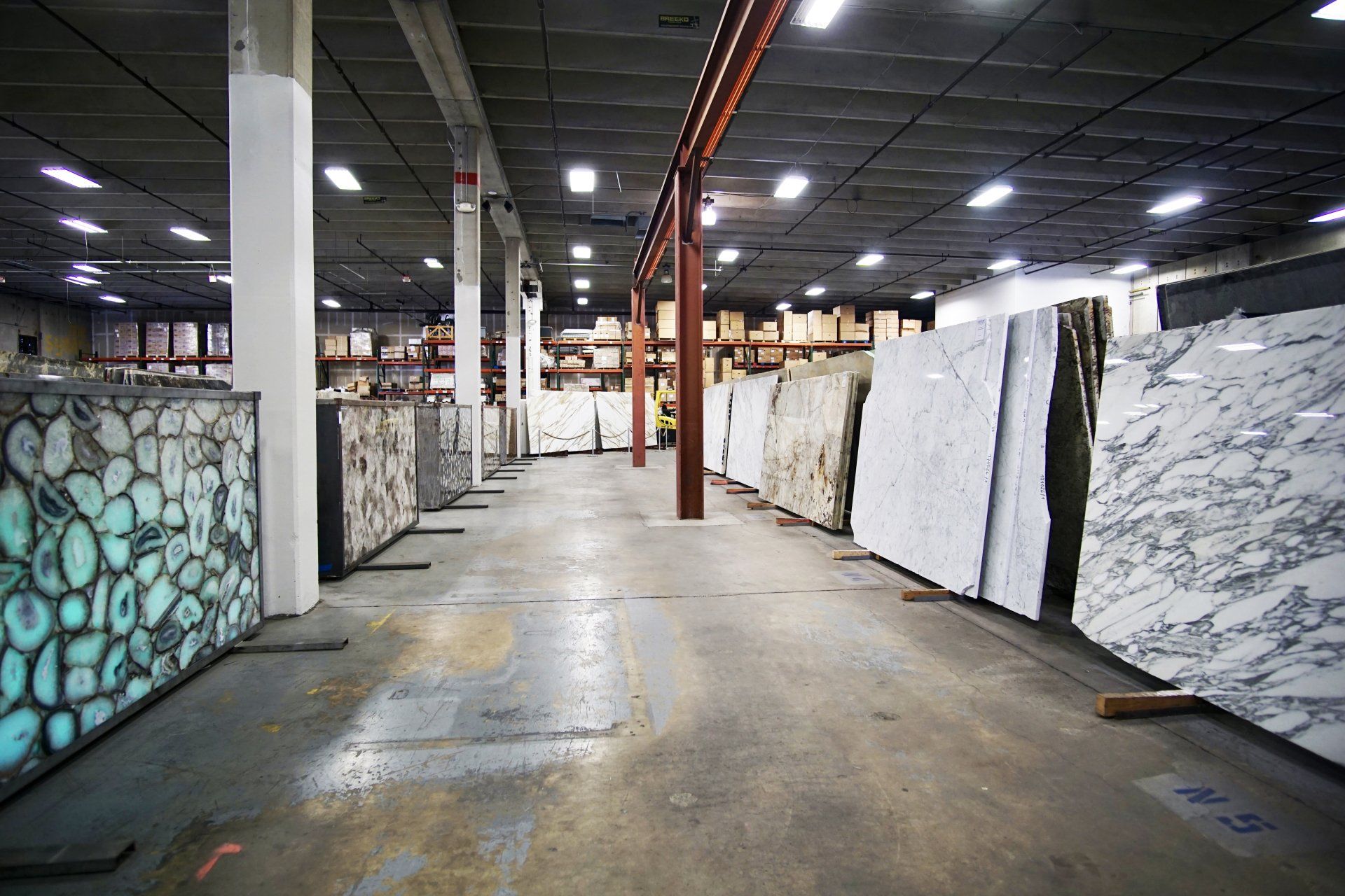 Warehouse interior with slabs of marble and granite standing upright.