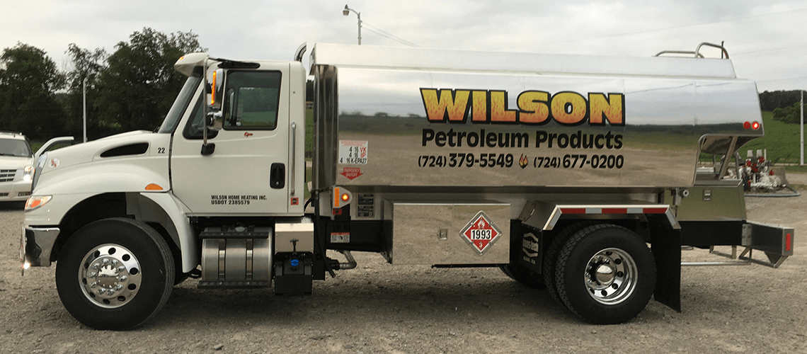 A white Wilson Petroleum Products tanker truck parked on a gravel lot.