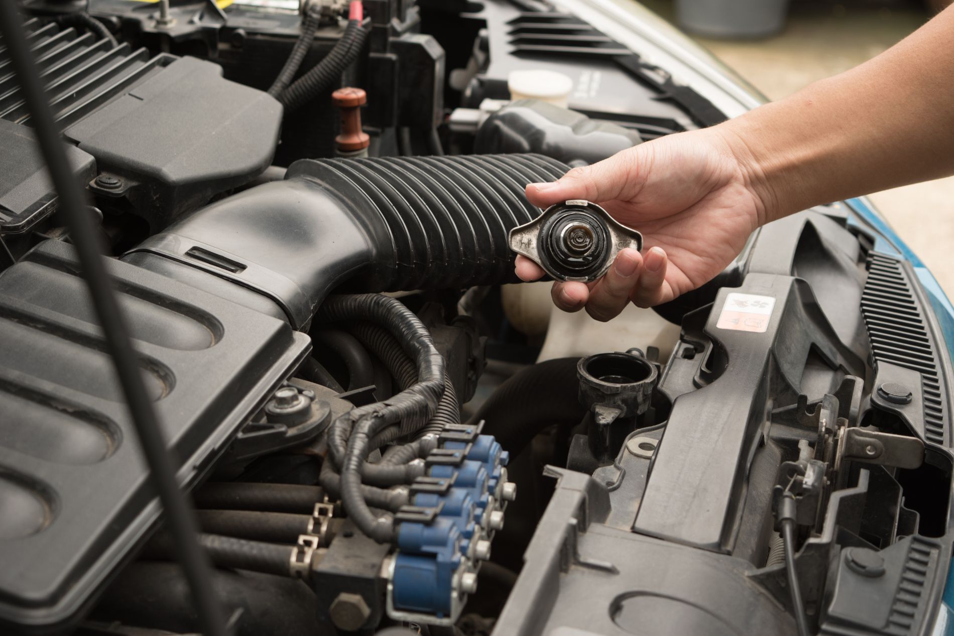 Technician inspecting engine components under the hood, cooling system service in Cincinnati, OH