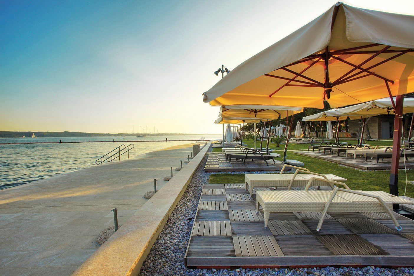 Una fila di sedie a sdraio sotto gli ombrelloni su una spiaggia di Portoroz