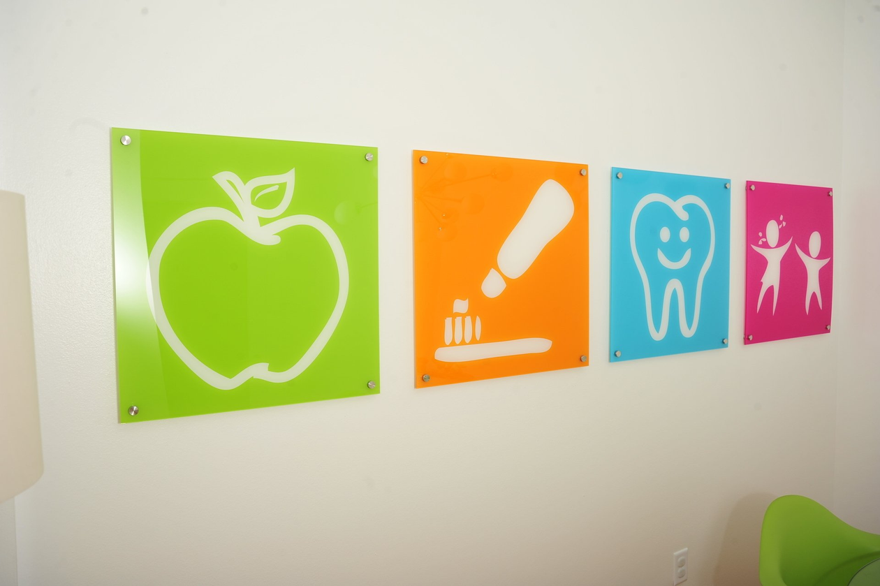 A row of colorful signs on a wall including an apple toothpaste and children