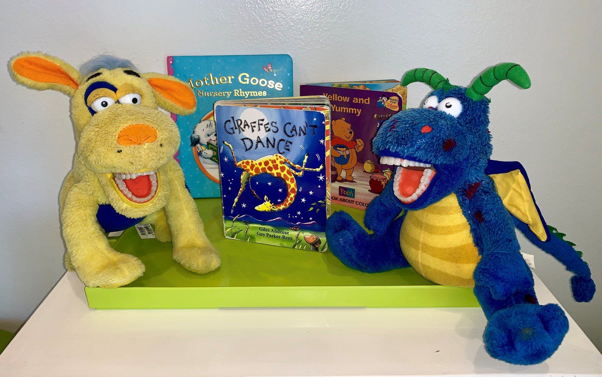 Two stuffed animals are sitting on a table next to books.