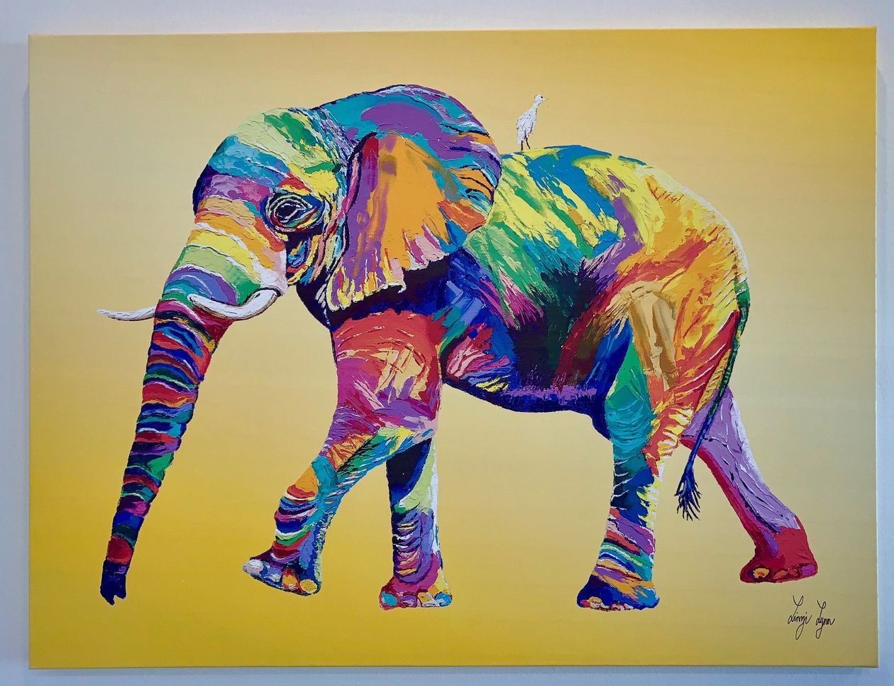 A painting of a colorful elephant on a yellow background