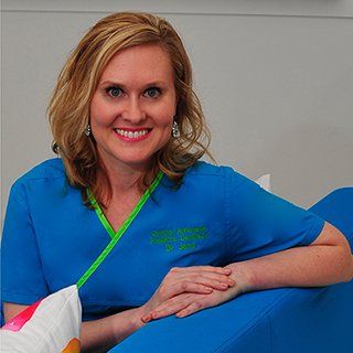 A woman in a blue scrub top is sitting on a blue couch